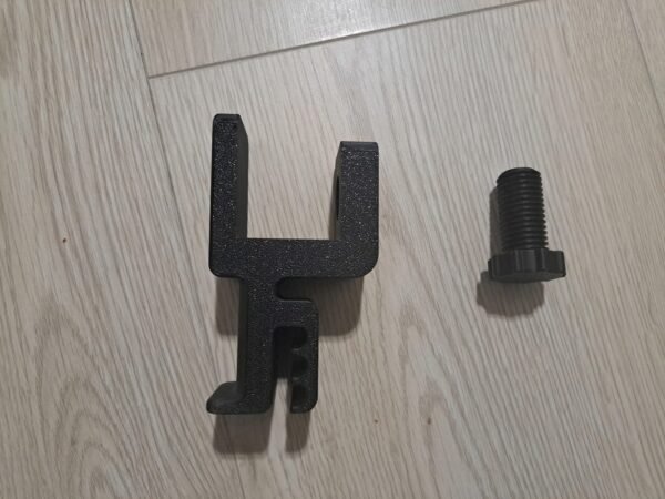 Musta kuuloketeline ja sen kiinnitysruuvi irrallaan vaalealla lattialla.