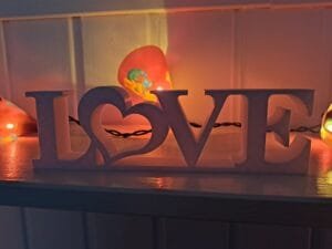 LOVE‑koriste sydämellä valkoisena sisustuselementtinä