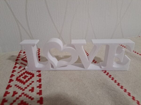 Valkoinen LOVE‑koriste sydämellä pöydällä