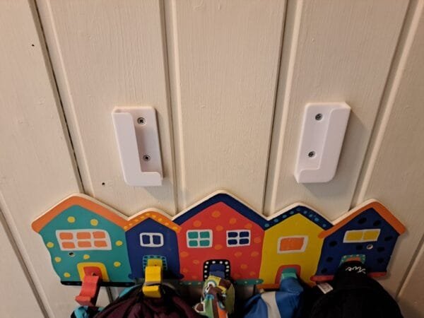Valkoiset tablettipidikkeet kiinnitettynä seinäpaneeliin