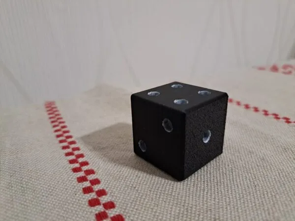 Musta 3D‑tulostettu noppa teksturoidulla pinnalla