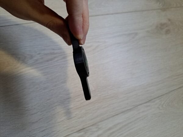 Musta muovinen kierrekorkin avaaja kädessä sivusta kuvattuna