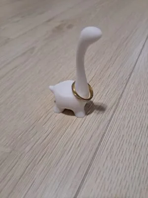 sormusteline_dino_sormuksen_kanssa2 Valkoinen muovinen dino-sormusteline, jossa kultainen sormus dinosauruksen kaulassa