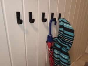 Mustat seinäkoukut käytössä takin ja sateenvarjon kanssa.